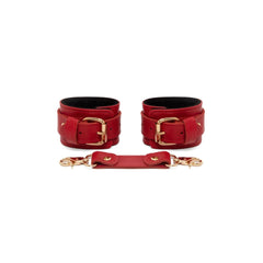 Red leather cuffs with gold buckles and a matching strap on a white background