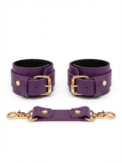 Purple leather cuffs with gold buckles on a white background