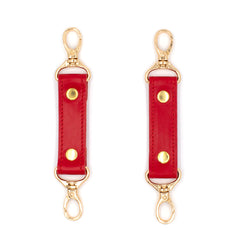 Two red leather connnectors with gold hardware on a white background